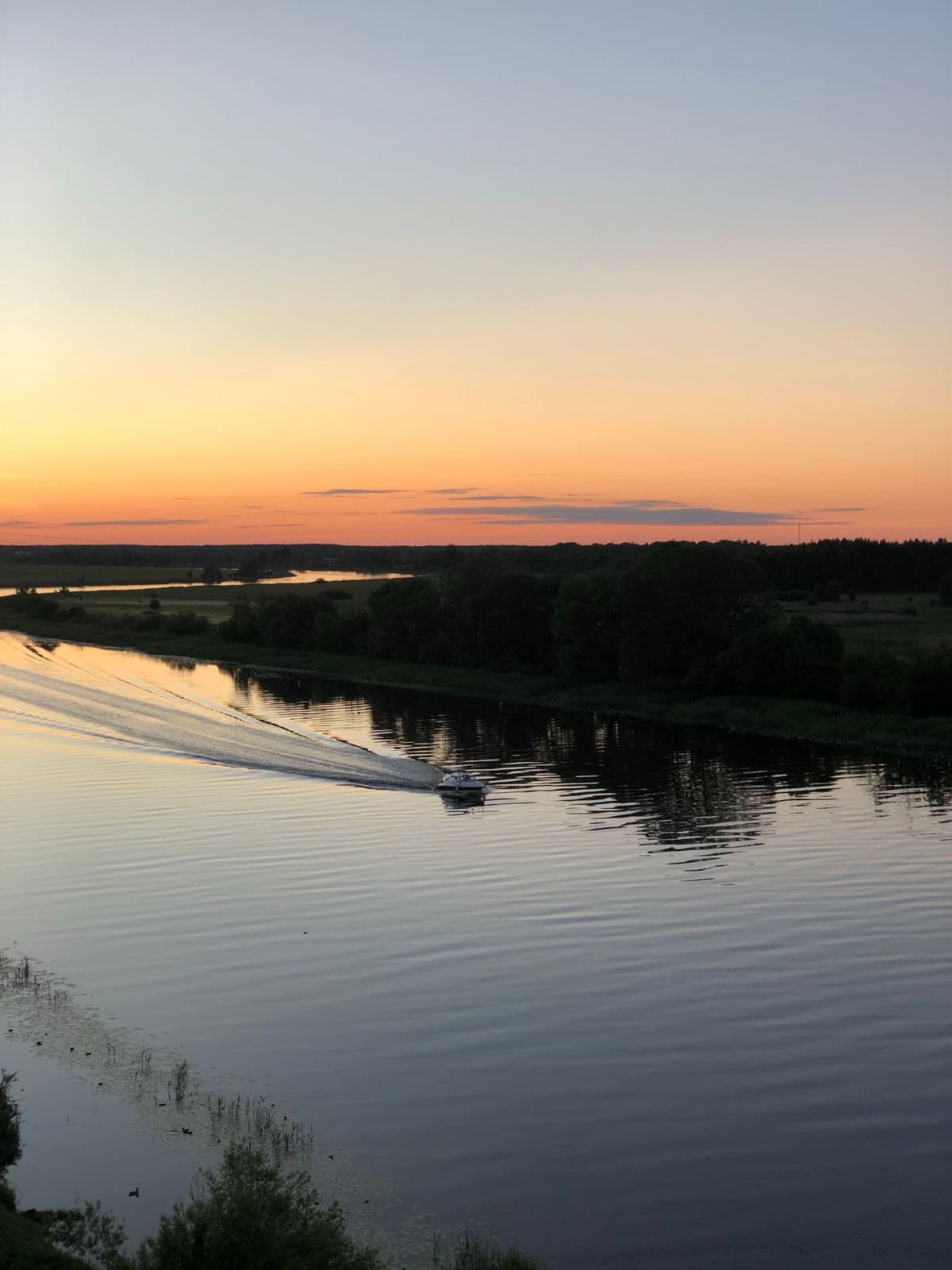Petit bateau sur une riviere au crepuscule, ciel orange et reflets