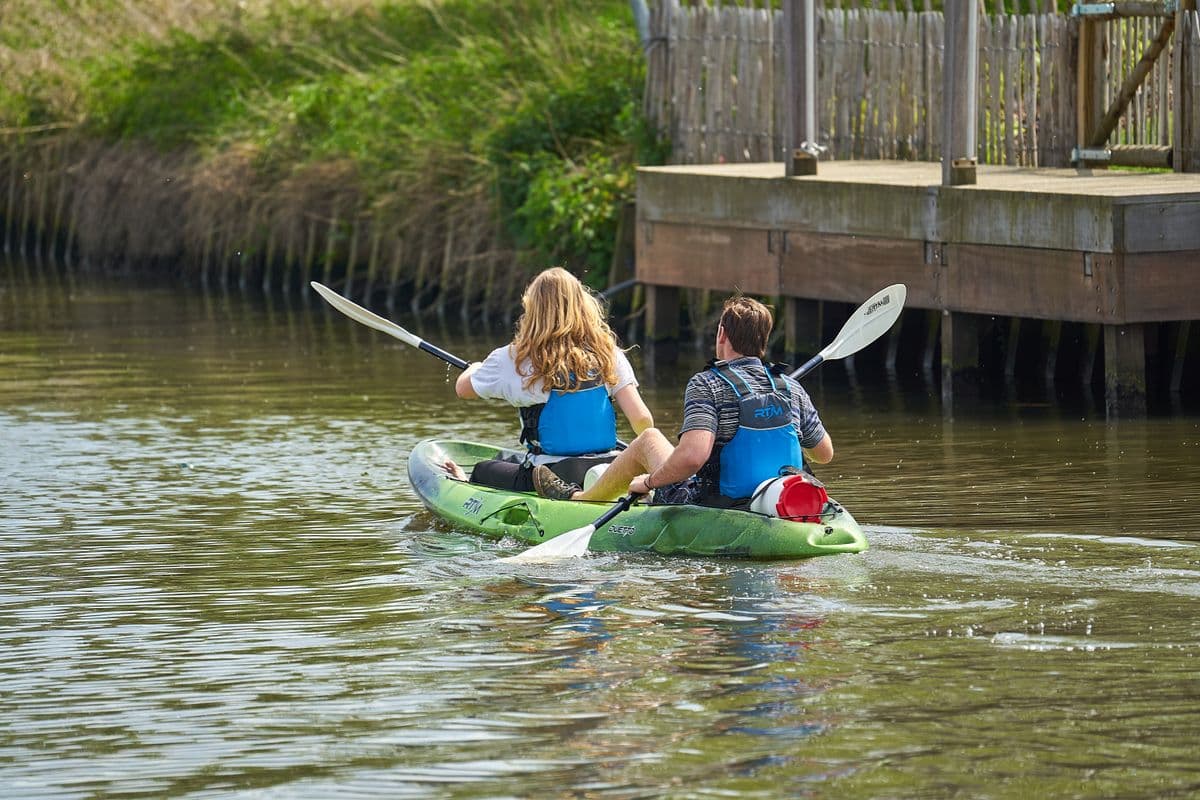 Couple pagayant en canoe sur une riviere calme et verdoyante