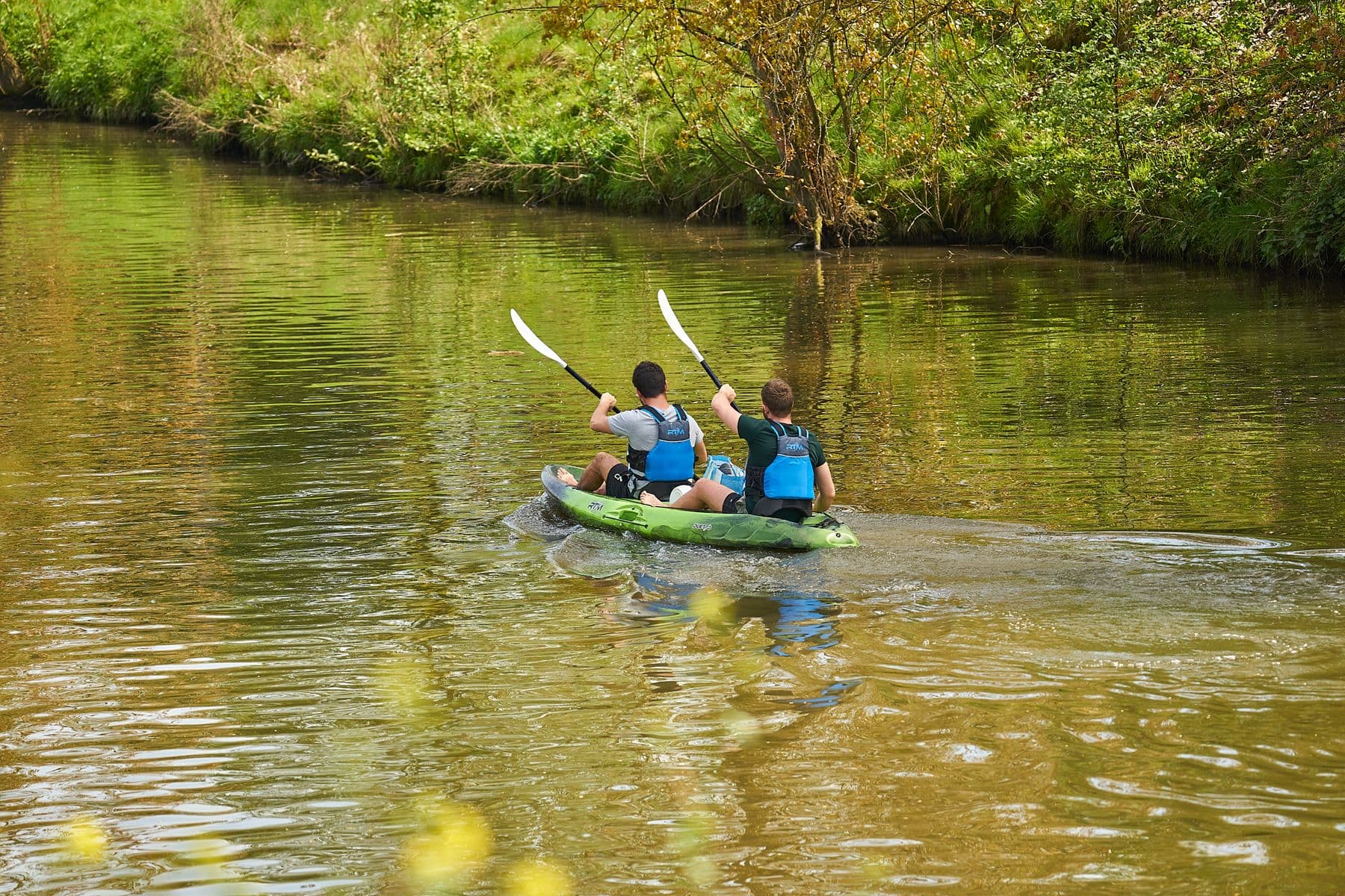 Deux personnes en canoë sur une rivière bordée de verdure à Moissac